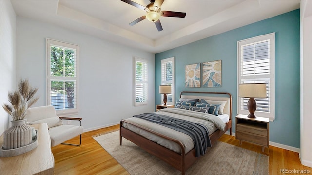 6187 Reed Way, Arvada, CO 80003 - bedroom with a tray ceiling, multiple windows, wood finished floors, and a ceiling fan