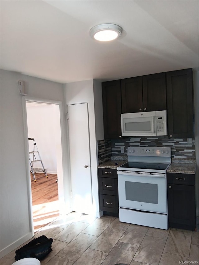 kitchen featuring white appliances, dark stone counters, and backsplash