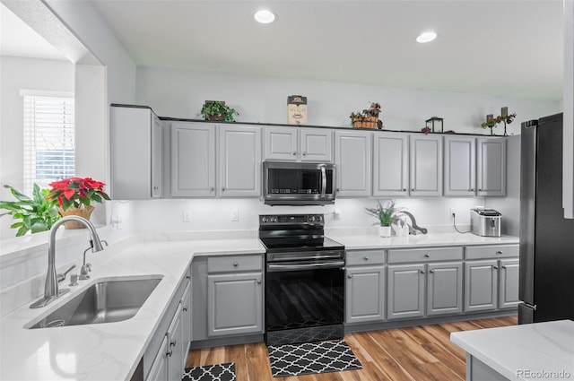 kitchen featuring light wood-type flooring, appliances with stainless steel finishes, gray cabinetry, and sink