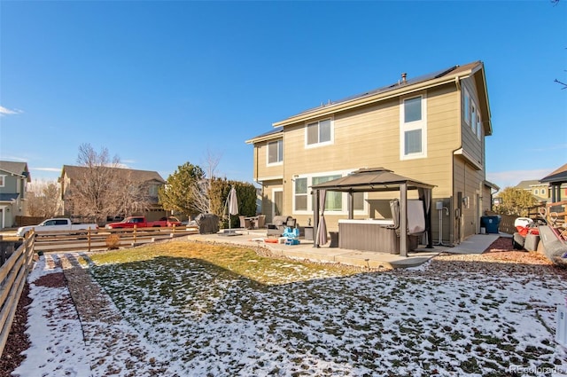 snow covered rear of property with a gazebo, a patio, and a jacuzzi