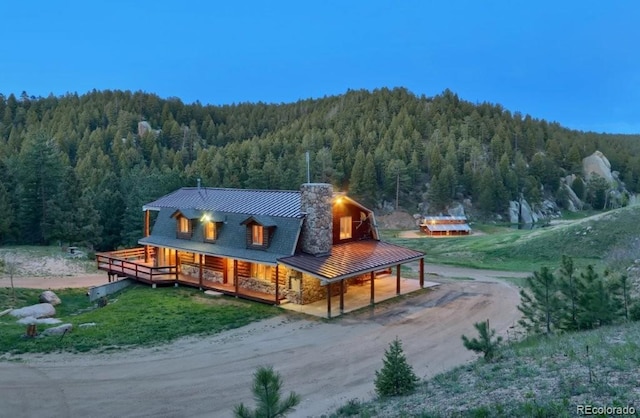 60 N County Highway 67, Sedalia, CO 80135 - back of house featuring a forest view, dirt driveway, covered porch, and a metal roof