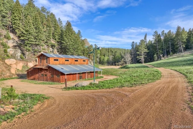60 N County Highway 67, Sedalia, CO 80135 - view of home's exterior with a wooded view, a barn, an outdoor structure, and a metal roof