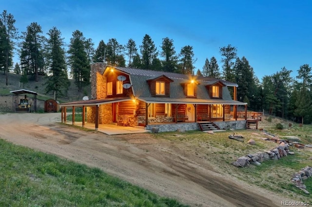 60 N County Highway 67, Sedalia, CO 80135 - view of front facade featuring a porch, a chimney, stone siding, driveway, and a metal roof