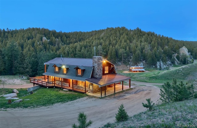 60 N County Highway 67, Sedalia, CO 80135 - back of house with a view of trees, dirt driveway, a porch, and a metal roof