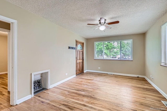 1325 Geneva St, Aurora, CO 80010 - unfurnished room with ceiling fan, light wood-style floors, a textured ceiling, baseboards, and a fireplace