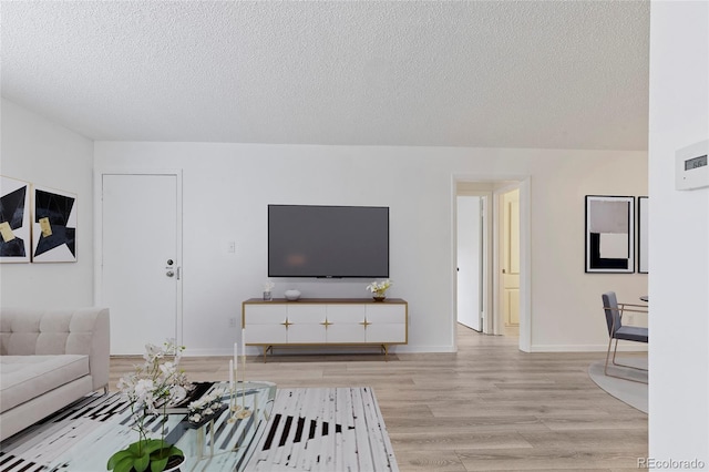 unfurnished living room featuring light wood-type flooring, baseboards, and a textured ceiling