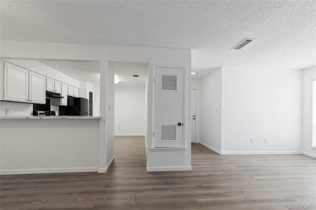 kitchen with visible vents, white cabinetry, freestanding refrigerator, and wood finished floors