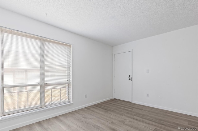 empty room featuring baseboards, a textured ceiling, and wood finished floors