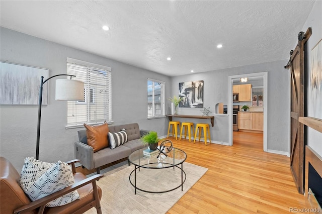 living room with recessed lighting, baseboards, light wood-style floors, and a barn door