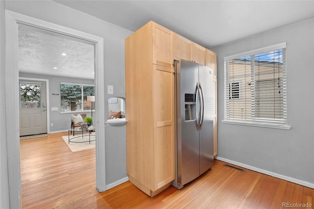 kitchen featuring light wood-type flooring, light brown cabinets, visible vents, and stainless steel fridge with ice dispenser