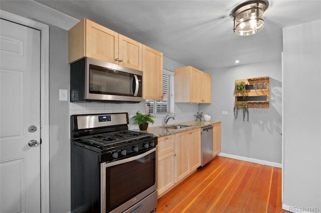 kitchen with light brown cabinets, tasteful backsplash, appliances with stainless steel finishes, and a sink