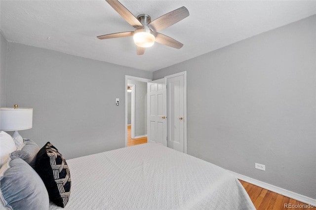 bedroom featuring a ceiling fan, baseboards, and wood finished floors