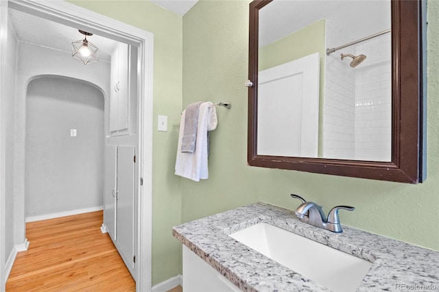 full bathroom featuring vanity, wood finished floors, baseboards, and a shower