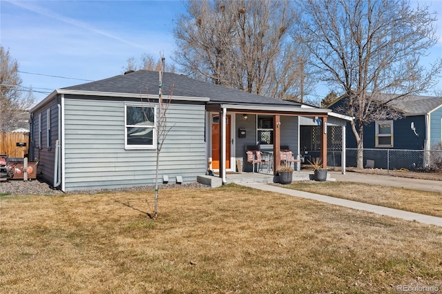 view of front of house with covered porch, fence, a front lawn, and roof with shingles