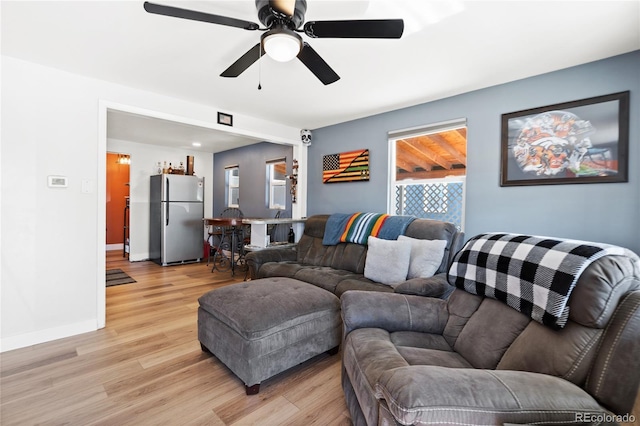 living room featuring light wood finished floors, ceiling fan, and baseboards