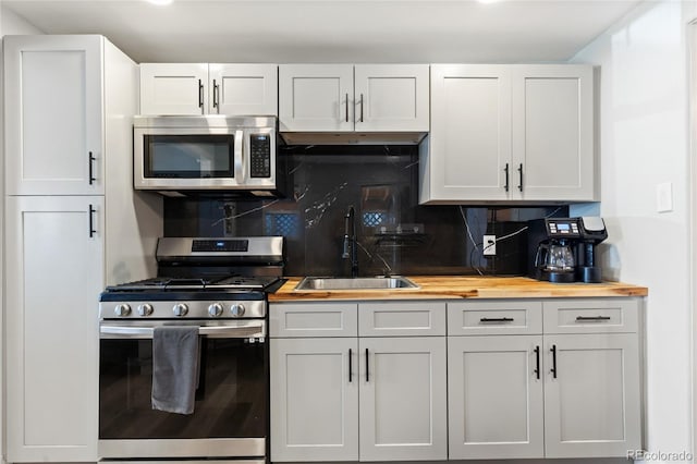 kitchen with tasteful backsplash, wooden counters, stainless steel appliances, and a sink