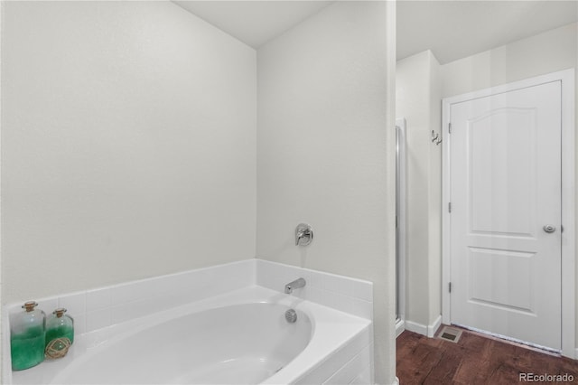 bathroom featuring hardwood / wood-style flooring and a relaxing tiled tub