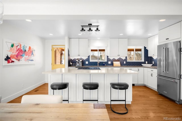 3925 Newland St, Wheat Ridge, CO 80033 - kitchen with high end refrigerator, decorative backsplash, a breakfast bar area, a kitchen island, and recessed lighting