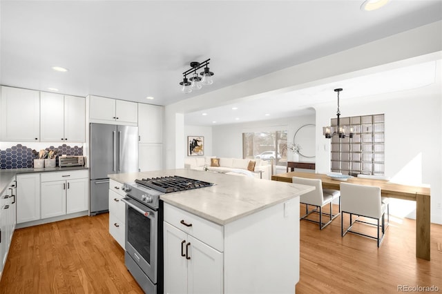3925 Newland St, Wheat Ridge, CO 80033 - kitchen with high quality appliances, light wood-type flooring, recessed lighting, white cabinetry, and decorative backsplash
