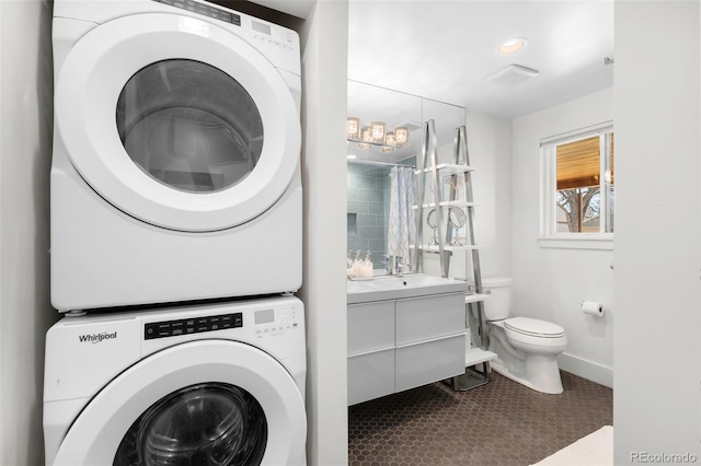 3925 Newland St, Wheat Ridge, CO 80033 - laundry area with stacked washer and clothes dryer, baseboards, and dark tile patterned flooring