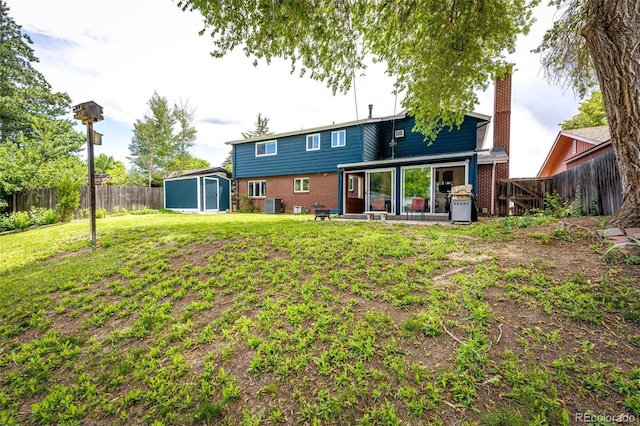 4645 W Temple Pl, Denver, CO 80236 - back of house with a storage shed, a fenced backyard, brick siding, and a patio
