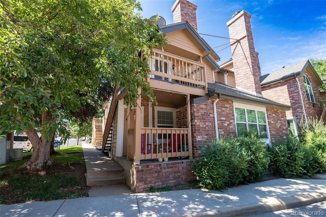 4943 S Carson St Unit 207, Aurora, CO 80015 - view of front of home with a chimney, brick siding, stairs, and a balcony