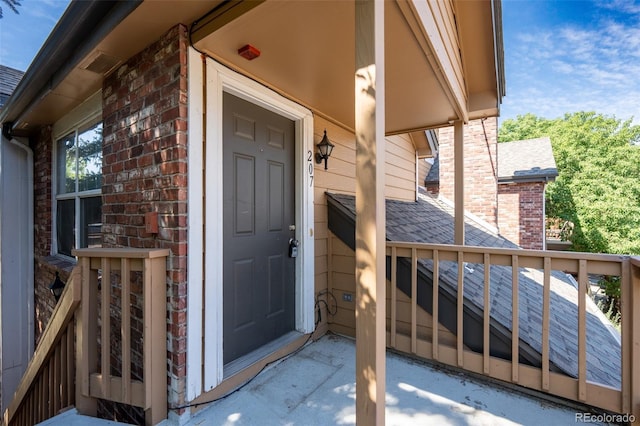 4943 S Carson St Unit 207, Aurora, CO 80015 - doorway to property featuring brick siding, a shingled roof, and a chimney
