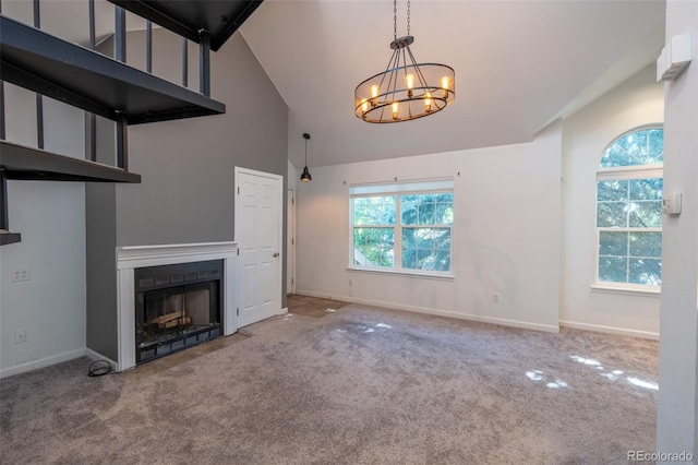 4943 S Carson St Unit 207, Aurora, CO 80015 - unfurnished living room featuring carpet flooring, high vaulted ceiling, a chandelier, and a fireplace with flush hearth