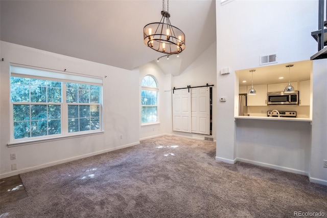 4943 S Carson St Unit 207, Aurora, CO 80015 - unfurnished living room with a barn door, carpet flooring, a chandelier, and high vaulted ceiling