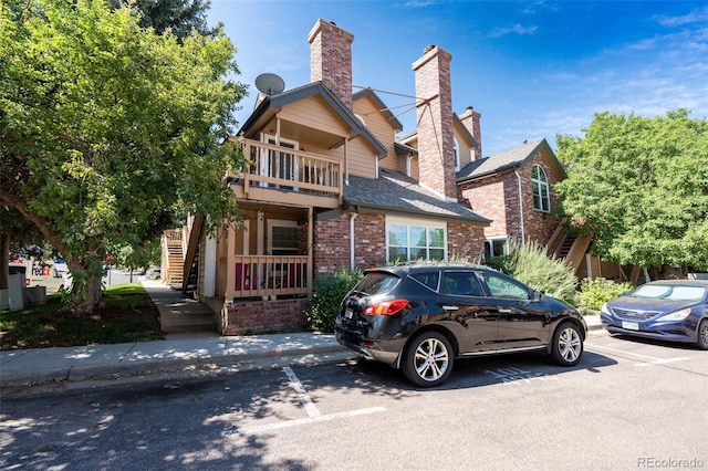 4943 S Carson St Unit 207, Aurora, CO 80015 - view of front of house with brick siding, stairs, a chimney, a balcony, and a shingled roof
