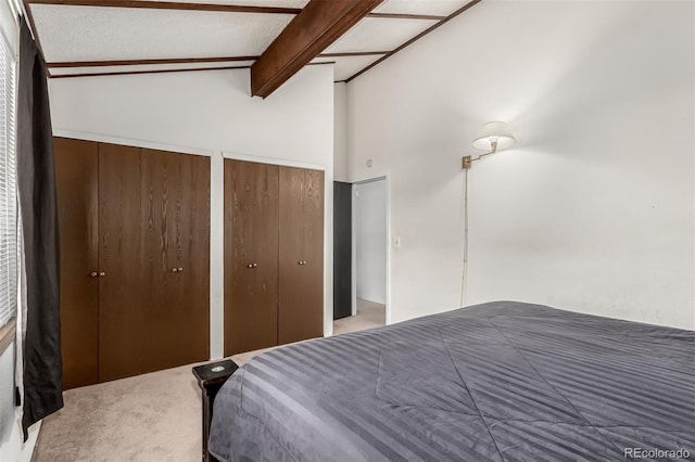 bedroom featuring carpet, lofted ceiling with beams, and two closets