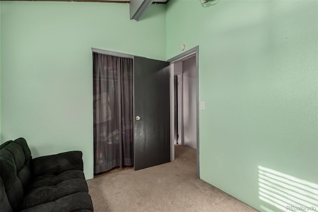 sitting room featuring carpet floors and vaulted ceiling with beams