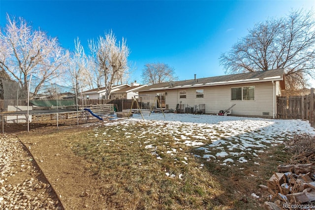 rear view of property with a trampoline and a fenced backyard