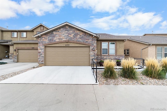 view of front of home featuring a garage, stone siding, driveway, and stucco siding