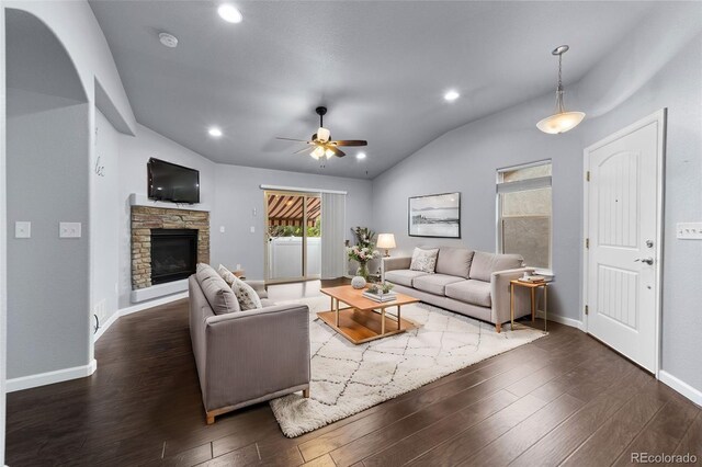 living room featuring a fireplace, dark wood-type flooring, ceiling fan, and vaulted ceiling