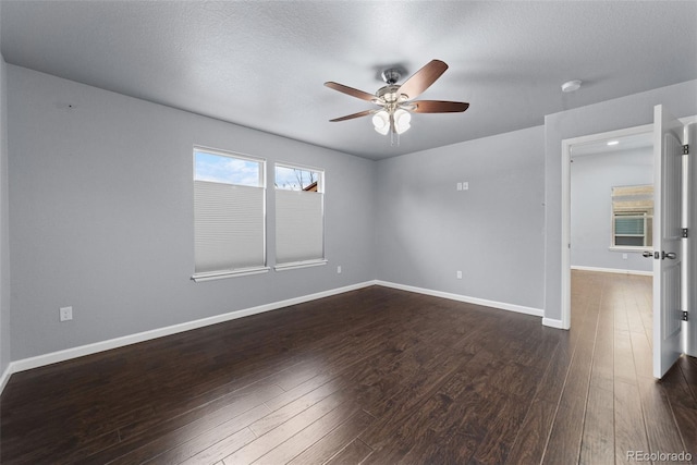 unfurnished room with ceiling fan, a textured ceiling, baseboards, and dark wood-type flooring