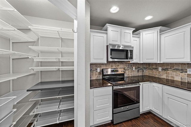 kitchen featuring dark wood finished floors, recessed lighting, backsplash, appliances with stainless steel finishes, and white cabinetry