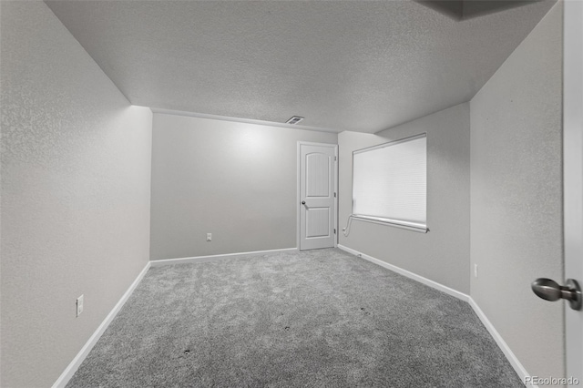 carpeted empty room with a textured ceiling, a textured wall, visible vents, and baseboards