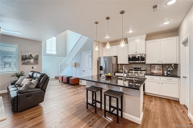 kitchen with appliances with stainless steel finishes, sink, a center island with sink, and white cabinets