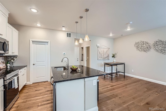 kitchen featuring a kitchen island with sink, white cabinetry, pendant lighting, and appliances with stainless steel finishes