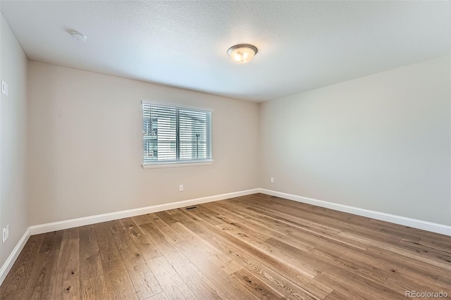 unfurnished room featuring hardwood / wood-style flooring and a textured ceiling