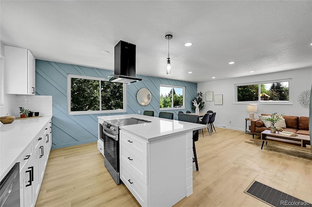 1173 Xenon St, Golden, CO 80401 - kitchen featuring electric range, island range hood, a breakfast bar, plenty of natural light, and a textured ceiling