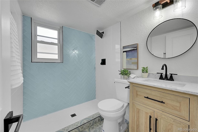 1173 Xenon St, Golden, CO 80401 - bathroom with vanity, toilet, a textured ceiling, tiled shower, and tile patterned flooring