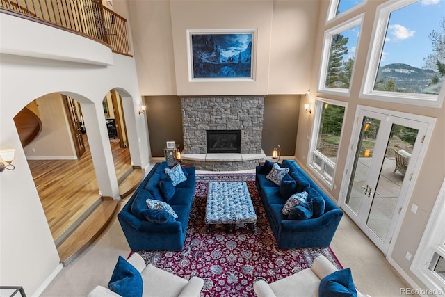 11406 Conifer Ridge Dr, Conifer, CO 80433 - living area with a high ceiling, arched walkways, a stone fireplace, baseboards, and french doors