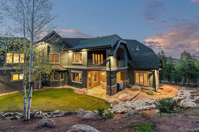 11406 Conifer Ridge Dr, Conifer, CO 80433 - back of property at dusk featuring a balcony, stucco siding, a yard, a patio, and metal roof