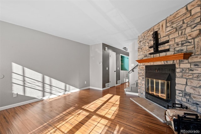 unfurnished living room featuring a stone fireplace and hardwood / wood-style floors