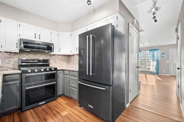 kitchen with gray cabinetry, white cabinetry, light hardwood / wood-style flooring, track lighting, and appliances with stainless steel finishes