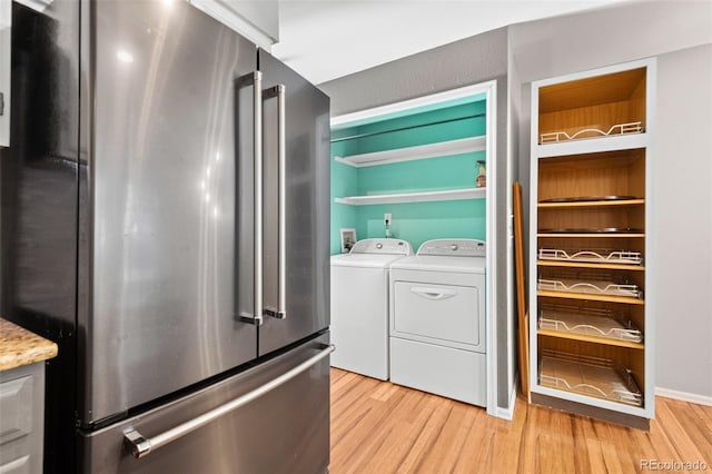 laundry room with separate washer and dryer and light hardwood / wood-style floors