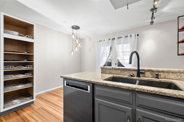 kitchen featuring light stone countertops, dishwasher, sink, hanging light fixtures, and light wood-type flooring