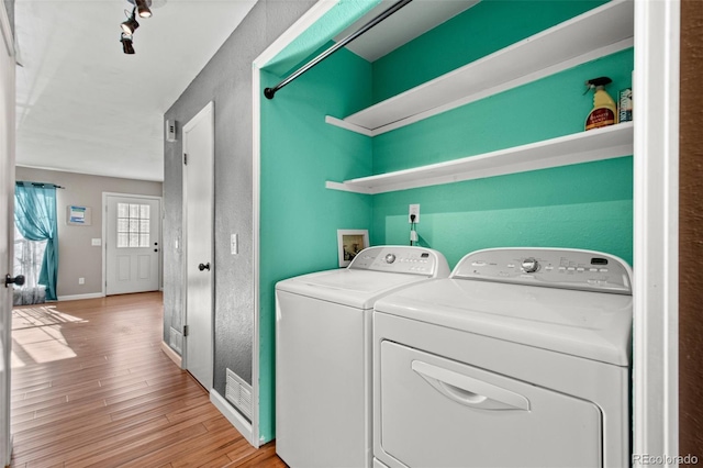 laundry area with washing machine and dryer and light wood-type flooring